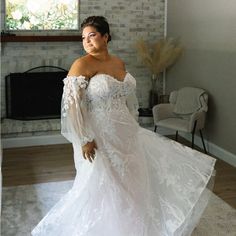 a woman in a white wedding dress posing for the camera with her hands on her hips