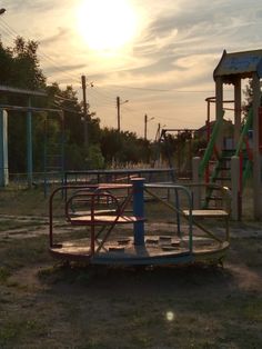 an empty playground with swings and slides in the background at sunset or sunrise, on a grassy area