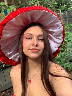 a woman wearing a red and white hat with flowers on it's head is posing for the camera