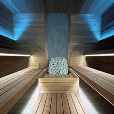 the inside of a sauna with wooden benches and lights on each side is lit up by blue lighting