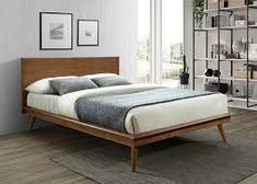 a bed sitting on top of a wooden floor next to a book shelf filled with books