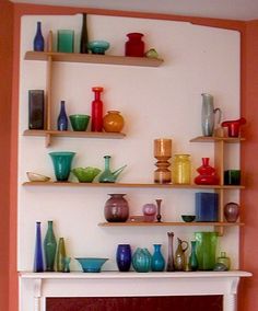 a fireplace with shelves filled with colorful vases and bowls on it's mantle