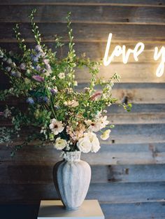 a vase filled with flowers sitting on top of a table next to a sign that says love you