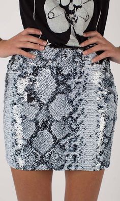 There is nothing that will constrict their heart like seeing you in the Any Old Iron Whitesnake Sequin Skirt! This mini, high-waisted, fitted skirt is decked out in a white snakeskin pattern, from the front to the back. While the pattern may appear to be printed on the skirt from afar, the closer you get to this slinky little number you will realize that this pattern is made entirely out of sequins alone. These sequins reveal shades of white and black all throughout; however, with the swipe of t Snakeskin Skirt, Sequin Kimono, Short Pollera, Rock Dresses, Vegas Style, Logo T Shirts, Snakeskin Pattern, Snake Design, Rock Chic