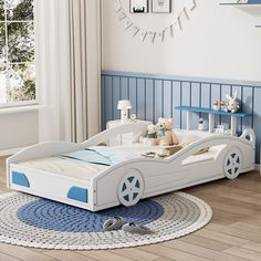 a child's bedroom with a white and blue car bed, toys and decor