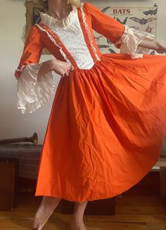 a woman in an orange and white dress is posing for the camera with her hands on her hips