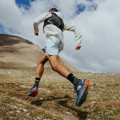 a man is running in the grass with a backpack on his back and shoes off