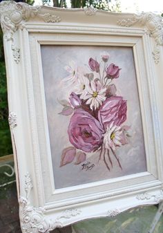 a white frame holding a painting of pink and white flowers in it's center