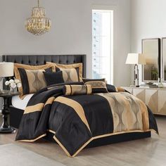 a bed with black and gold comforters in a room next to a chandelier