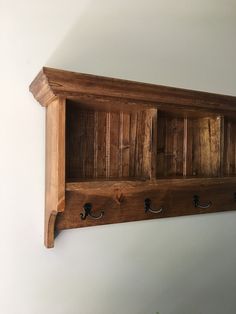 a wooden shelf with three hooks on it