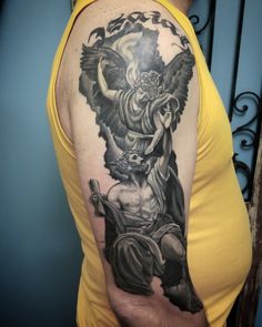 a man with a tattoo on his arm and shoulder holding an angel in the air