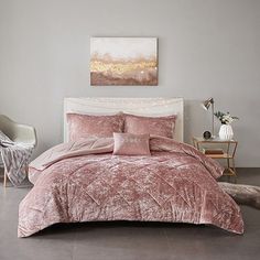 a bed with pink comforter and pillows in a room next to a painting on the wall