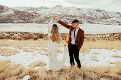 a bride and groom standing in the snow with mountains in the background at their wedding