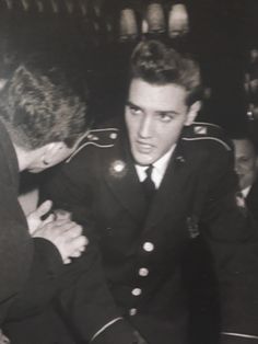 an old photo of a man in uniform being comforted by another man's arm