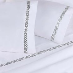 a bed with white sheets and two pillow cases on top of eachother,