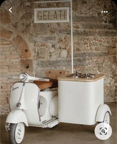 an old fashioned vespa is parked in front of a sign that says gelati