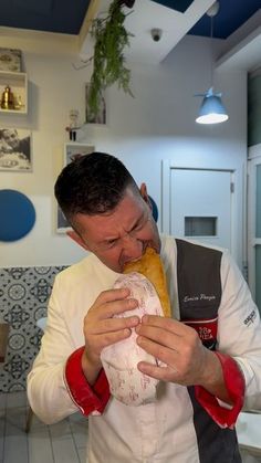 a man is taking a bite out of a large baguette in the kitchen