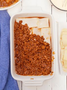 a casserole dish with meat and cheese in it next to other dishes on a table