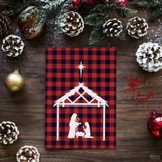 a christmas card with a nativity scene and pine cones on the table next to it