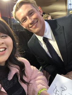 a man in a tuxedo poses for a photo next to a smiling woman