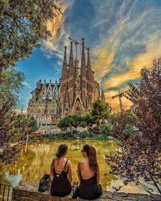 two women sitting on a bench in front of a cathedral