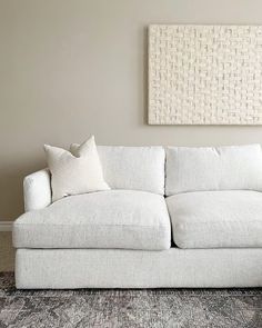 a white couch sitting in front of a wall with a painting on the wall behind it