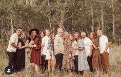 a group of people standing next to each other in a field with trees behind them