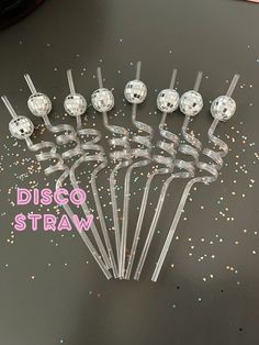 a bunch of silver disco balls sitting on top of a table next to confetti sticks