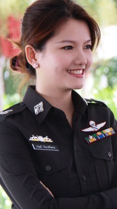 a woman in uniform is smiling and looking at the camera with her arms folded over her chest