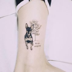 a small black and white dog tattoo on the ankle