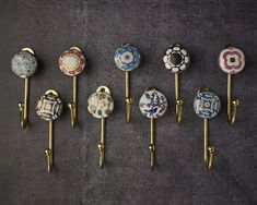 six decorative knobs are lined up in a row on a gray surface, one is gold and the other is multicolored