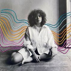 a woman is sitting on the floor with colorful lines coming out of her face and hair