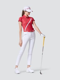 a woman in white pants and red shirt holding a golf club