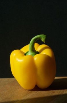 a yellow pepper sitting on top of a wooden table