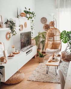 a living room filled with lots of plants and wicker furniture in front of a flat screen tv