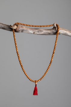 Each of these mala necklaces is made of 108 handcrafted Mala beads strung together with a red tassel. Traditionally used in Buddhist meditation, mala beads are used for counting all types of mantras, prayer, and meditations. When not in use, these beads are traditionally worn around the left wrist as a reminder to enrich the mind. The tassel marks the middle of the beads for counting. As a sign of respect, please do not let your mala beads touch the ground. Rosewood – a beautiful ebony wood asso Natural Wooden Beads Necklace For Meditation, Spiritual Wooden Beads Necklace For Meditation, Spiritual Necklace With 108 Natural Beads, Holistic Wooden Beads Mala For Rituals, Holistic Wooden Mala For Rituals, Traditional Necklace With 108 Natural Color Beads, Traditional Natural Necklace For Meditation, Spiritual Wooden Beads Mala For Meditation, Holistic Mala With 108 Beads For Meditation