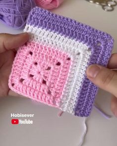 a hand holding a small crocheted square