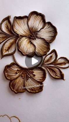 an embroidered flower is shown on the side of a piece of paper with gold thread