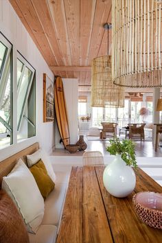 a living room filled with furniture next to a wooden table and window covered in bamboo shades