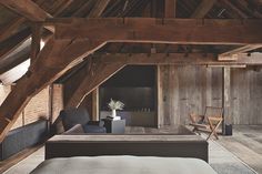 an attic bedroom with wooden walls and exposed ceilings, has a large bed in the center