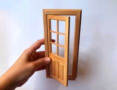 a hand is holding up a small wooden door