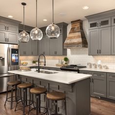 a kitchen with gray cabinets and white counter tops, an island with stools next to the stove