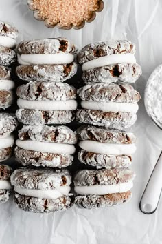 a pile of doughnuts sitting on top of a table next to a bowl of powdered sugar