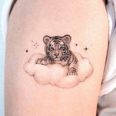 a tiger cub sitting on top of a cloud with stars in the sky behind it