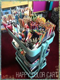 a cart filled with lots of different colored pens and pencils on top of a red carpet