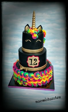 a three tiered cake decorated with an unicorn's horn and number 12 on top