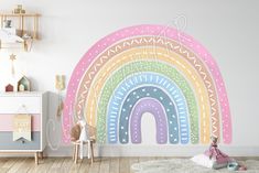 a child's room decorated in pastel colors with a rainbow wall decal