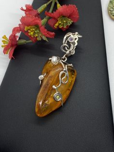 "ARTISAN AMBER GEMSTONE PENDANT Hand-made Sterling Silver. Stones used: Baltic Amber, Pearls, Peridot, Amethyst. Height - 73mm, Width - 30mm. Unique Handcrafted One-of a-kind Design Pendant Each Piece of Jewelry in my Collection is Absolutely One of a Kind! When you start wearing a piece of my jewelry you will fall in love with it more and more each day and feel that good Energy and Love that I pass into it while creating this piece of Art. A piece of Art created for you to be inspired and love Elegant Gemstone Pendant Beads, Elegant Gemstone Pendant, Handmade Elegant Round Pendant Gemstones, Elegant Freeform Gemstone Jewelry, Hallmarked Wedding Pendant Gemstones, Elegant Handmade Citrine Gemstones, Handmade Elegant Citrine Gemstones, Handmade Elegant Pendant Beads, Gems, And Cabochons, Unique Cabochon Necklaces For Wedding