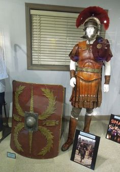 an old roman soldier costume and helmet on display in a glass case with other items