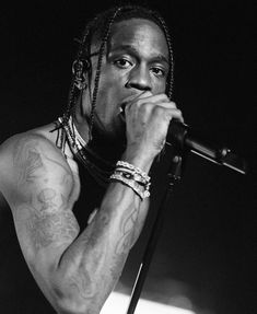 a black and white photo of a man with dreadlocks singing into a microphone